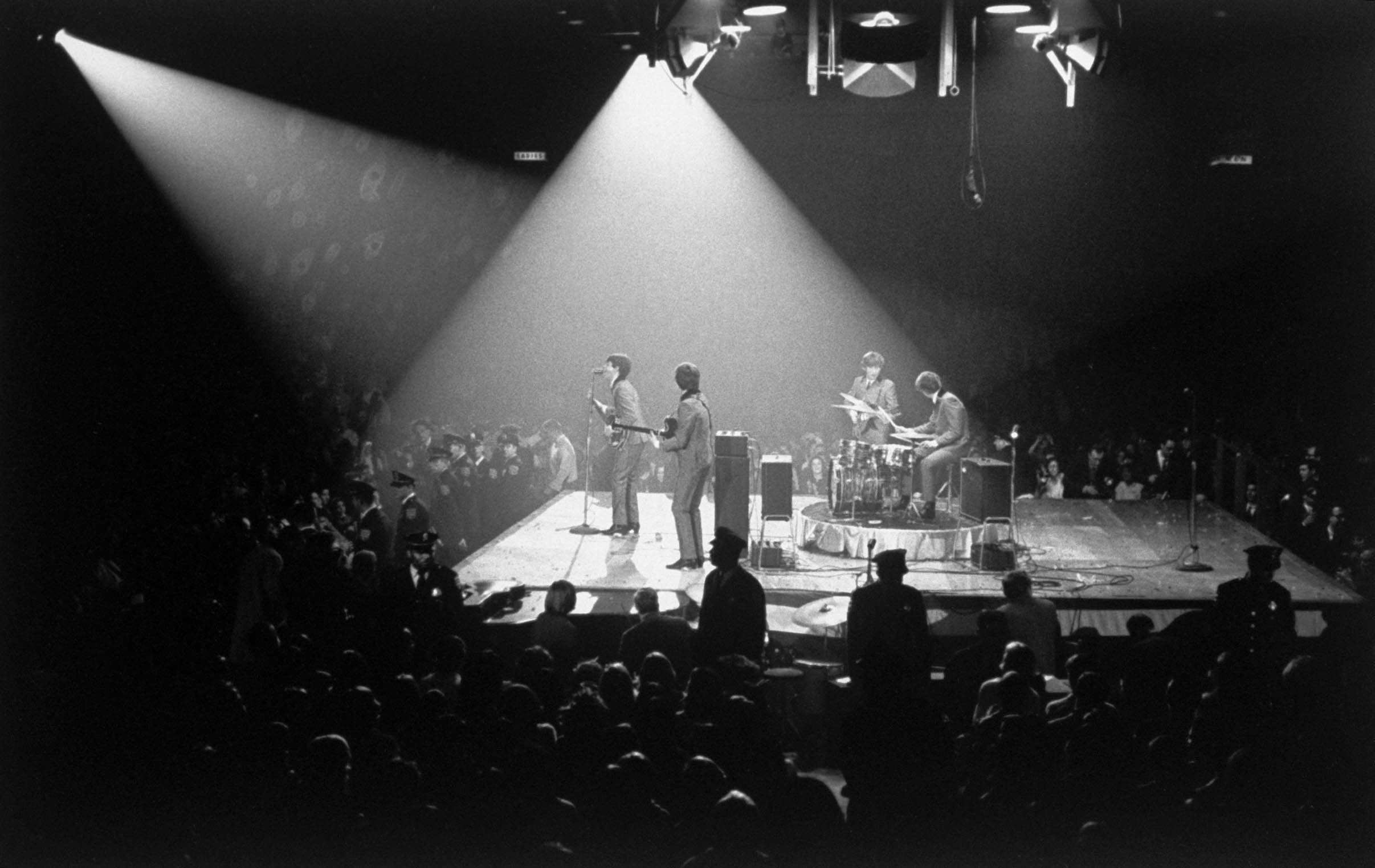 The Beatles (Paul McCartney, George Harrison, John Lennon & Ringo Starr) on stage in concert panorama during the first Beatles concert in America.