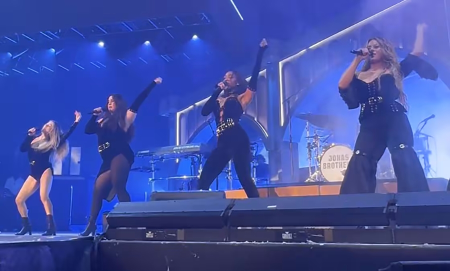 Here’s a descriptive, SEO-friendly alt text for this image: Fifth Harmony perform together on stage during their reunion at a Jonas Brothers concert in Dallas, with all four members singing in coordinated black outfits.